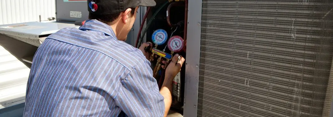 HVAC technician servicing a condenser unit in Lorain
